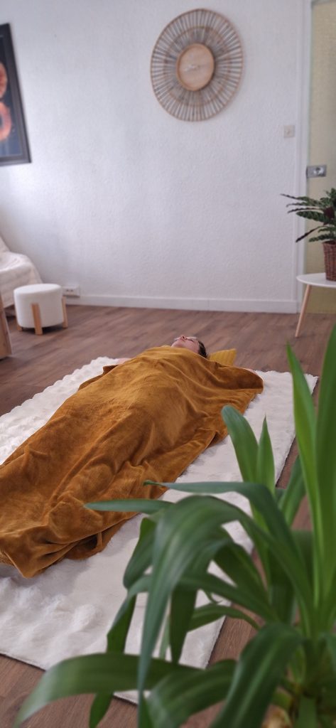 Personne allongée sous une couverture pendant une séance de sophrologie en cabinet
