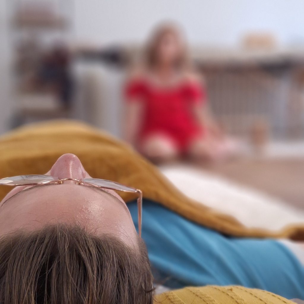 Séance de sophrologie : une participante allongée sur un tapis, la sophrologue assise à ses côtés