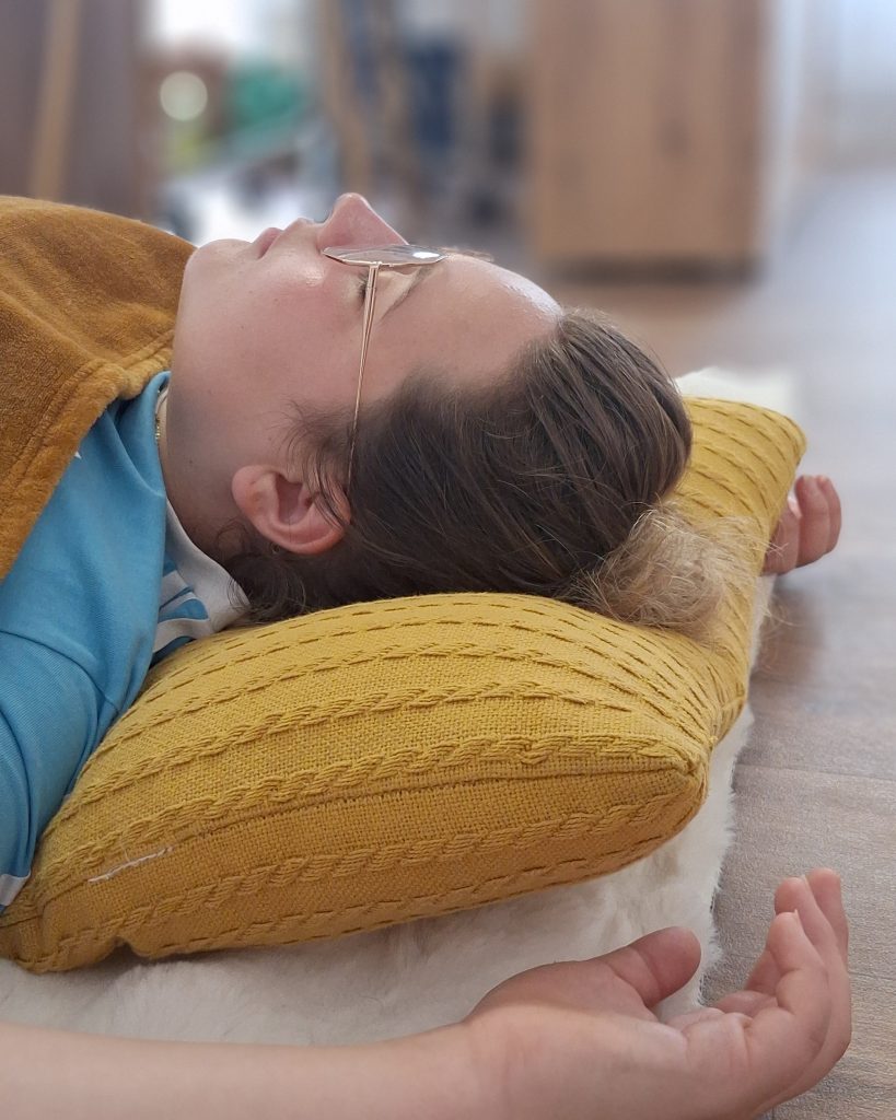 Participante allongée sur un coussin, les yeux fermés, pendant une séance de sophrologie individuelle