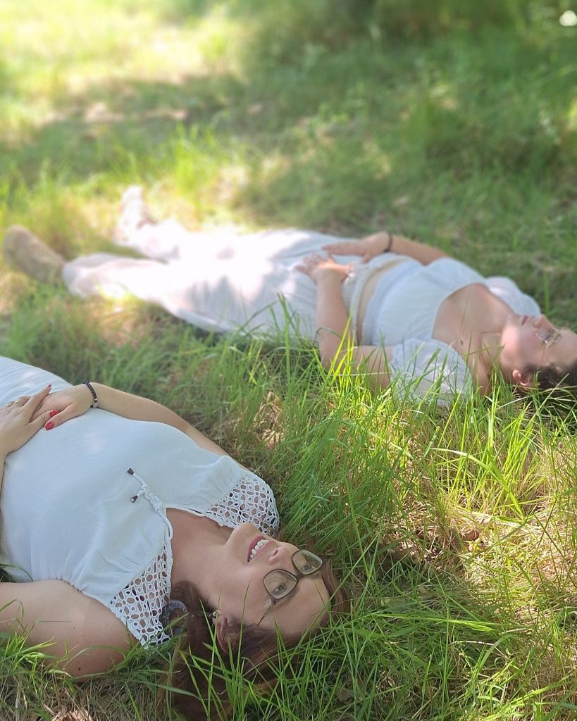Deux participantes allongées dans l'herbe pendant un atelier de sophrologie en nature