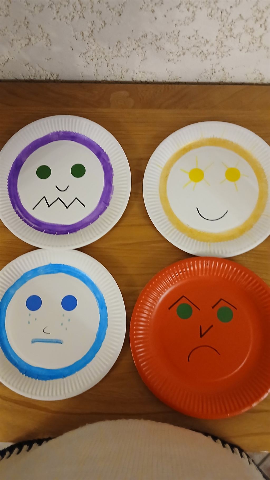 Quatre assiettes en carton peintes en visages d'émotions (peur, joie, tristesse, colère), exercice utilisé pendant les séances enfants